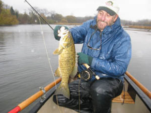 Tim in the rain with smallmouth on a white cactus bugger.