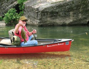 Angler in canoe with a nice limestone stream smallmouth bass