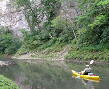 A river kayak angler in front of limestone bluffs