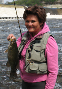 A wade angler with smallmouth bass near a dam
