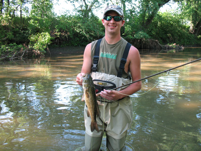 Young angler standing in a stream with smallmouth bass