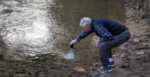 closeup of Steve Witham putting ashes int the water